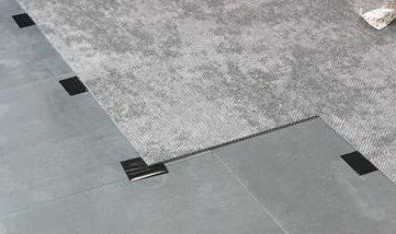 Grey carpet tiles laid on steel floor using small black squares